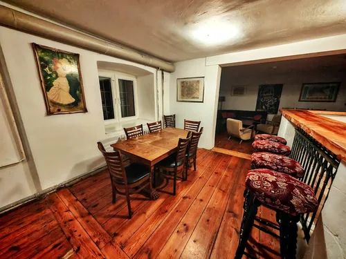 Bar im Souterrain mit Holztresen, Barhockern und langer Tafel