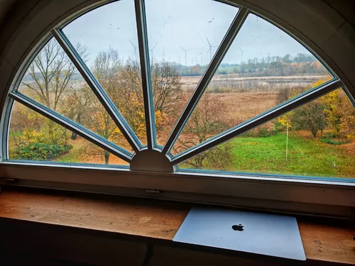 Arbeitsplatz mit Laptop vor einem halbrunden Fächerfenster
